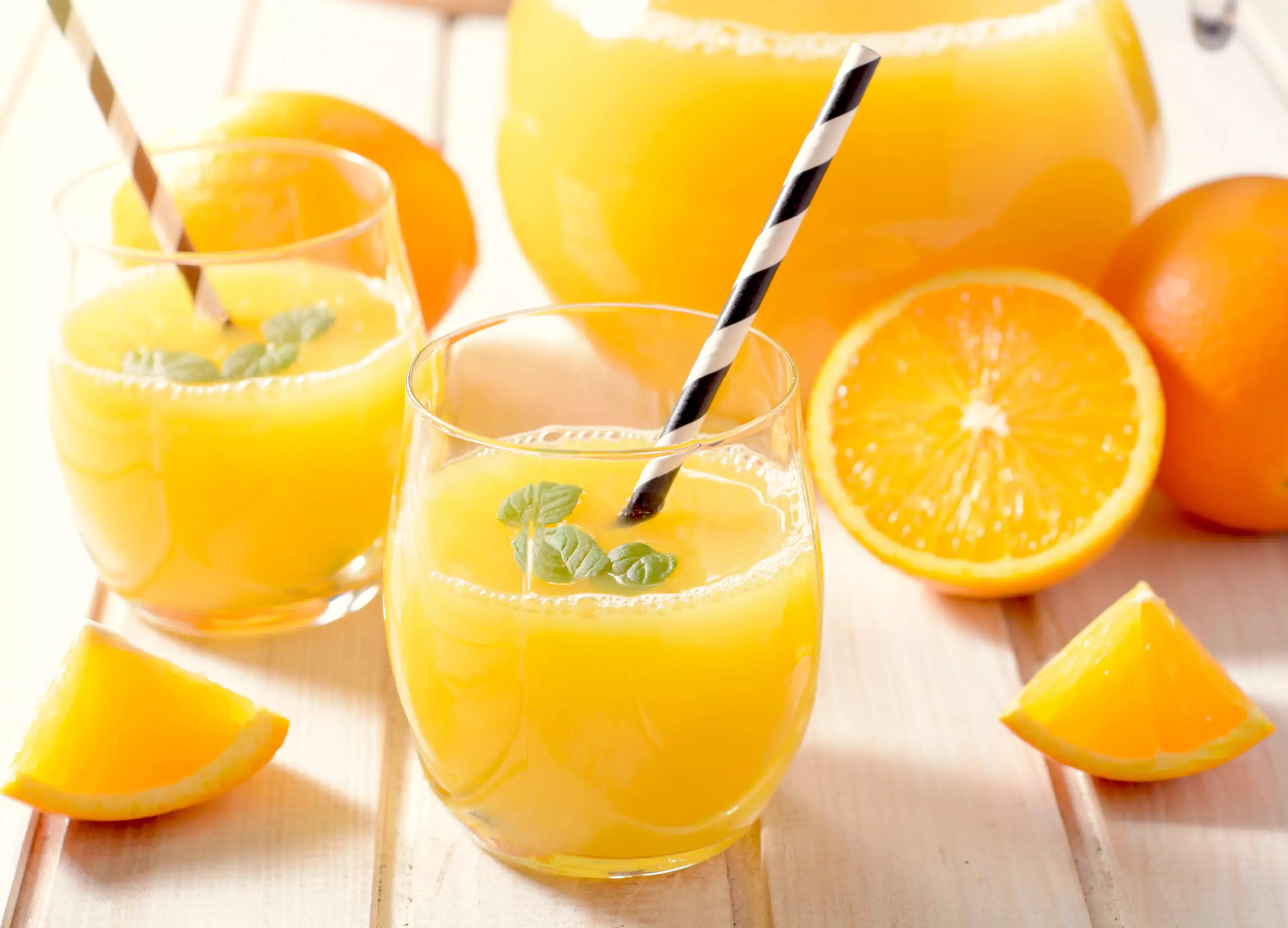 Fresh orange juice in glasses with mint garnish.