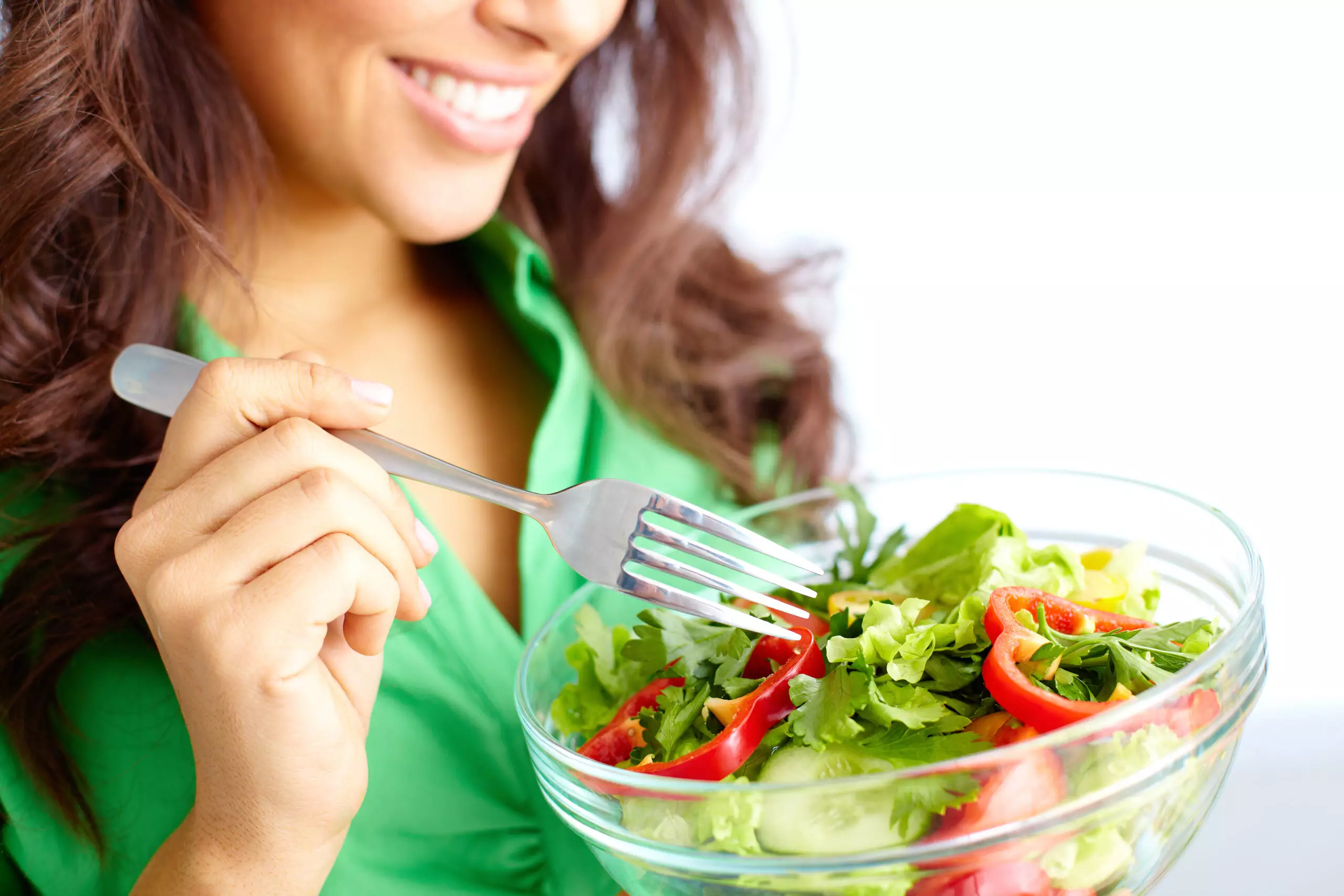 Woman smiling, eating fresh vegetable salad.