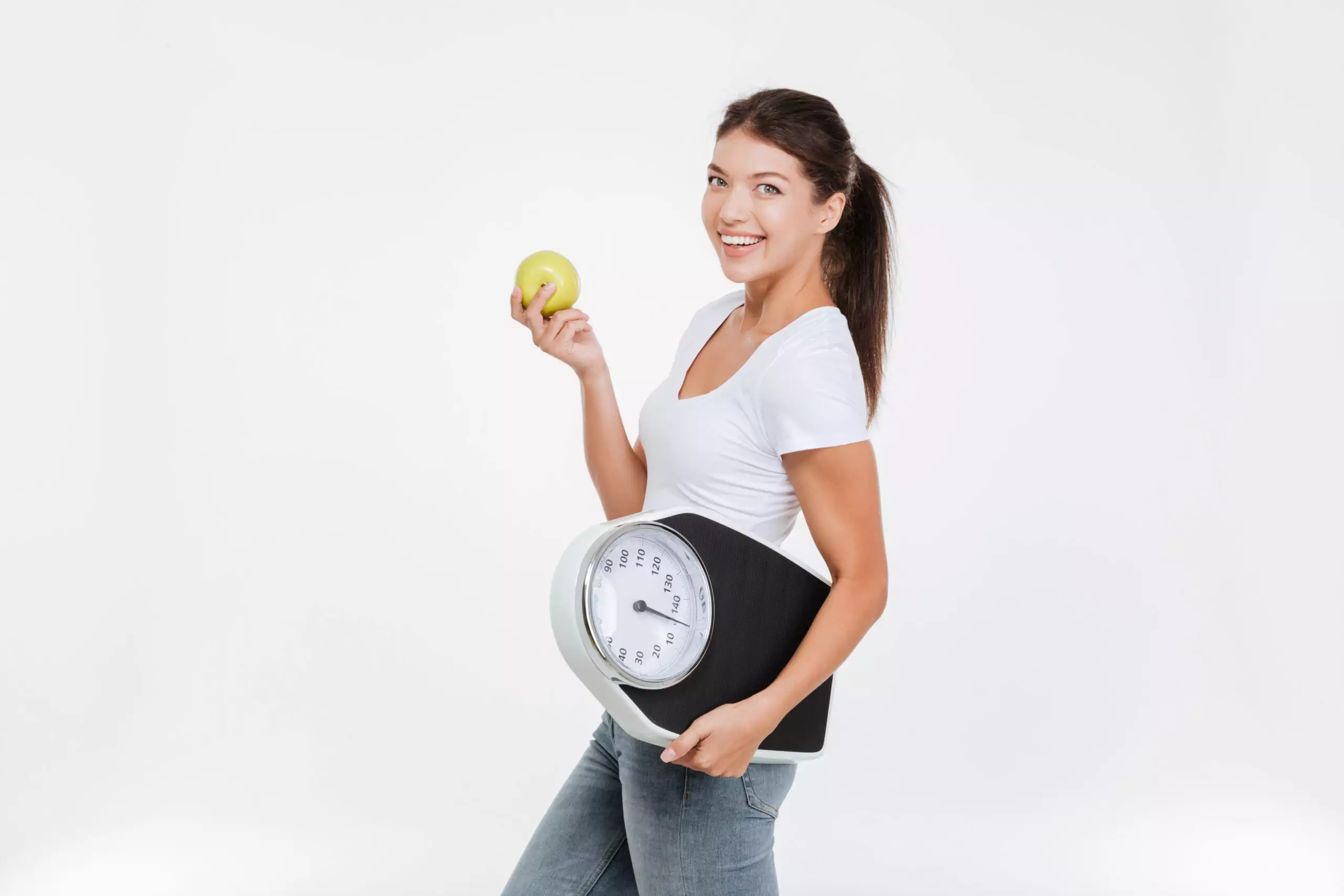 Woman holding apple and scale, promoting healthy lifestyle.