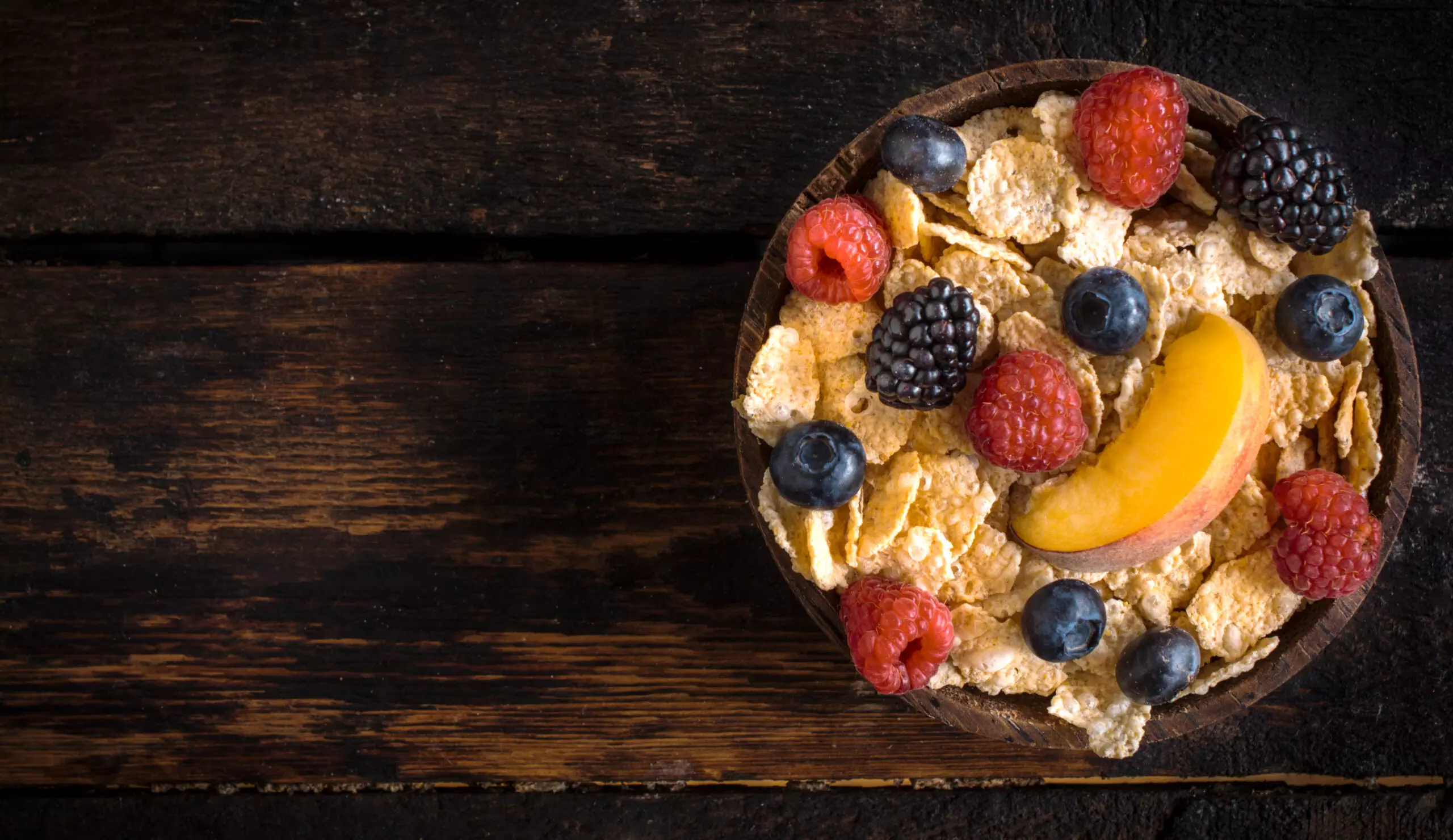 Healthy cereal with fresh berries in wooden bowl.