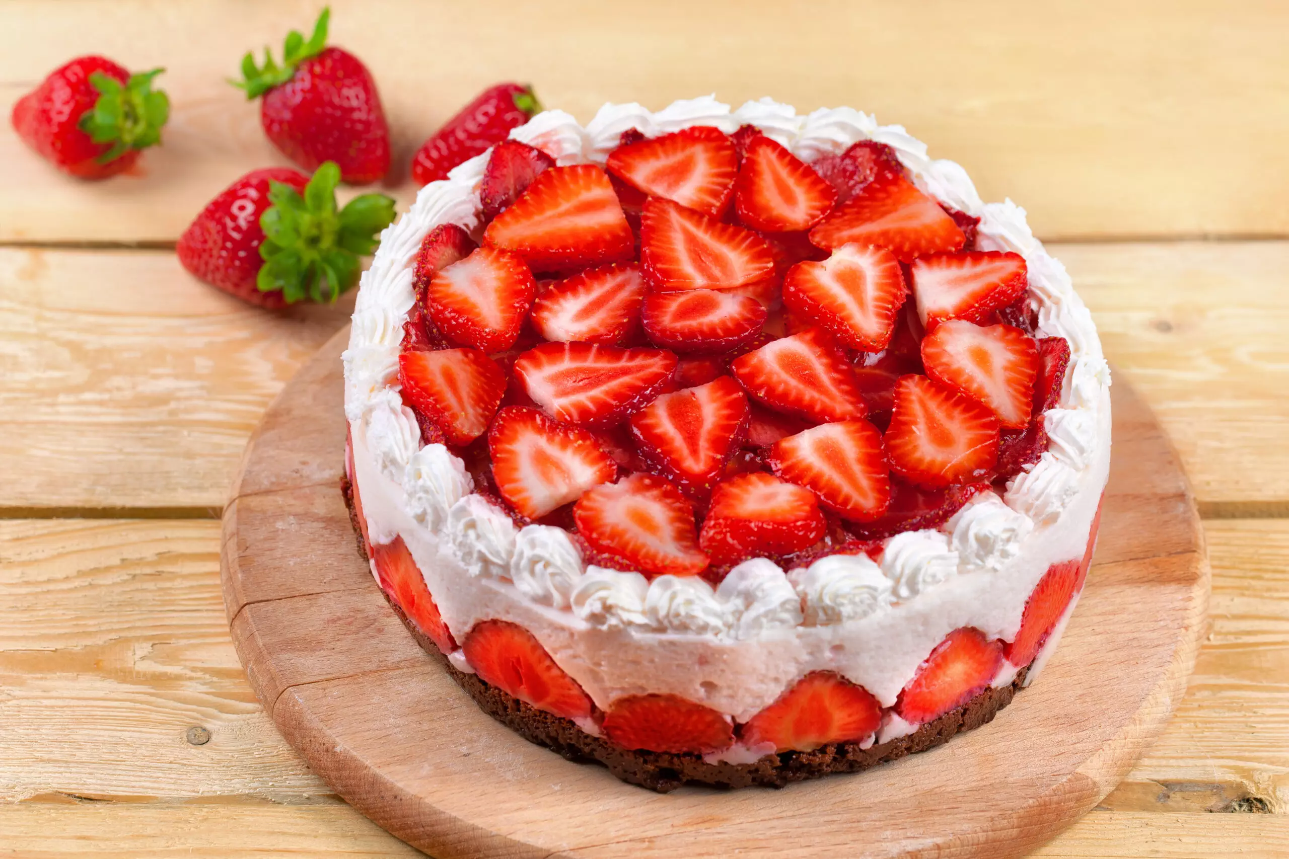 Fresh strawberry cream cake on wooden background